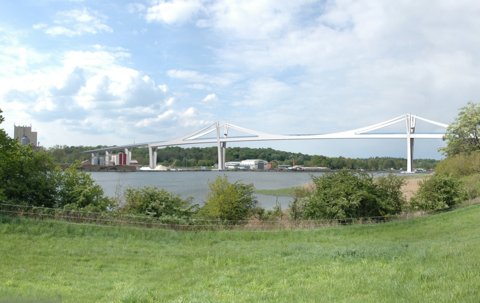 Am Ufer eines Flusses, der Peene, stehen Bäume. Im Hintergrund führt eine Brücke mit zwei Pylonen über das Gewässer. Auf der anderen Uferseite ist ein Industriegelände.