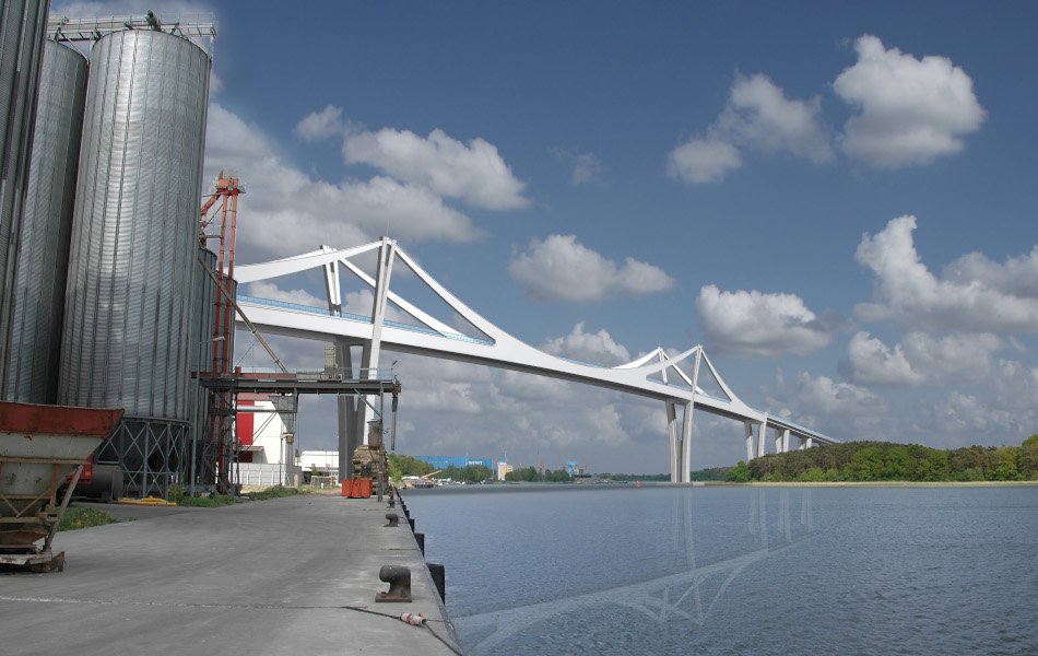 Über ein Gewässer, die Peene, führt eine Brücke mit zwei Pylonen. Auf der linken Uferseite stehen Silos, auf der rechten Bäume. Im Hintergrund ist die Werft.