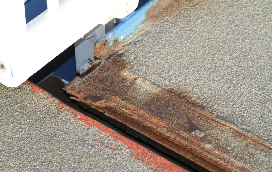 Zwischen zwei Fahrbahn-Abschnitten auf der Brücke ist ein kleiner Spalt. Die Kanten der Fahrbahnen sind rostig.