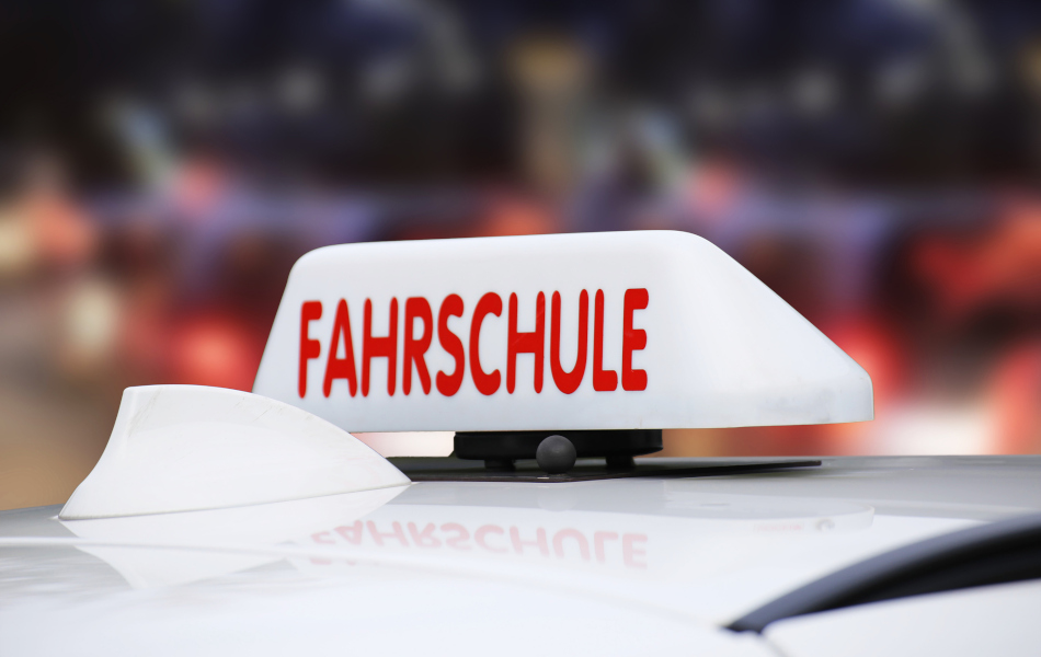 Ein Schild mit der Aufschrift "Fahrschule" ist auf einem Autodach. 