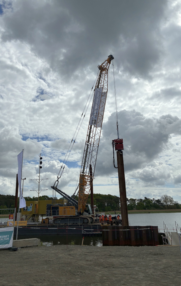 Rammeinheit und Kran auf der Baustelle der Peenestrombrücke am Uferbereich. © strassen-mv.de Rammeinheit und Kran auf der Baustelle der Peenestrombrücke am Uferbereich.
