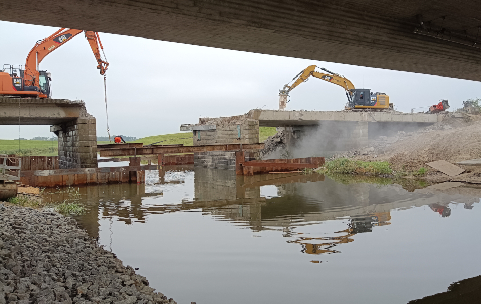 Eine alte Brücke führt über einen Fluss. Auf der Brücke stehen zwei Bagger und tragen das Bauwerk ab. © strassen-mv.de Eine alte Brücke führt über einen Fluss. Auf der Brücke stehen zwei Bagger und tragen das Bauwerk ab.