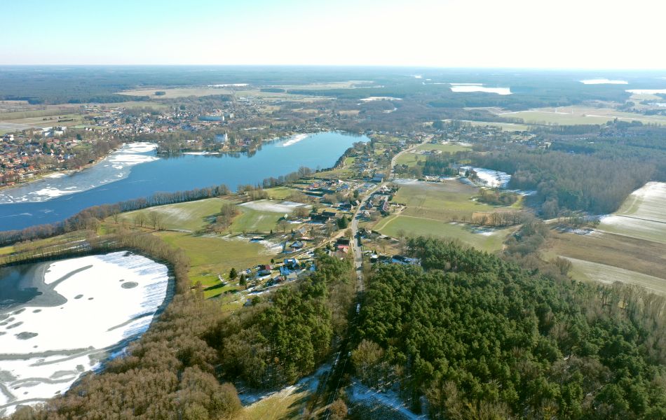 Blick von oben auf die Stadt Mirow, die an zwei Seen liegt. Auf dem Wasser ist Schnee und Eis zu sehen. Mitten durch den Ort führt eine Straße, die B 198.