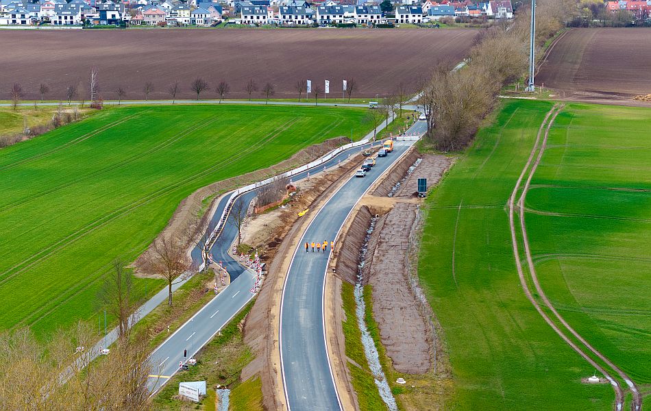 Auf einer Straße stehen mehrere Autos und Menschen mit orangenen Schutzjacken gehen auf der Straße, um diese zu begutachten. Parallel zu der Straße verläuft eine weitere Straße. © Pixelbox15 Auf einer Straße stehen mehrere Autos und Menschen mit orangenen Schutzjacken gehen auf der Straße, um diese zu begutachten. Parallel zu der Straße verläuft eine weitere Straße.