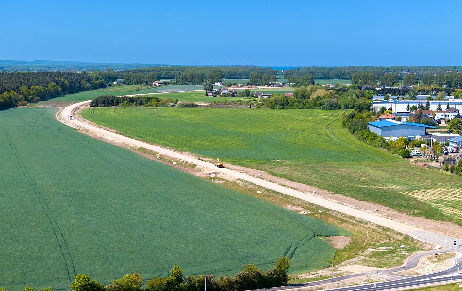 Von einer Straße geht eine Trasse ab, die aus Erde und Schotter besteht und über Felder an einem Ort (Elmenhorst) vorbeiführt. Auf der Trasse ein Bagger und ein Lkw. © Pixelbox15 Von einer Straße geht eine Trasse ab, die aus Erde und Schotter besteht und über Felder an einem Ort (Elmenhorst) vorbeiführt. Auf der Trasse ein Bagger und ein Lkw.