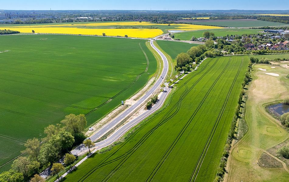 Aus einer Straße werden zwei Straßen: Die eine Straße führt in einen Ort (Elmenhorst) hinein. Die andere Straße führt über Felder um die Ortschaft herum. © Pixelbox15 Aus einer Straße werden zwei Straßen: Die eine Straße führt in einen Ort (Elmenhorst) hinein. Die andere Straße führt über Felder um die Ortschaft herum.