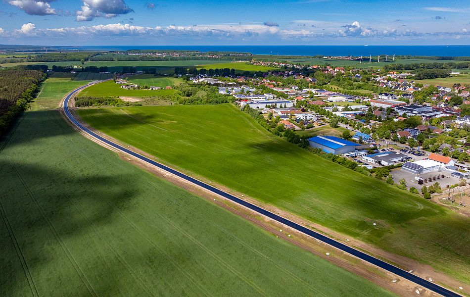 Eine frischasphaltierte Straße führt über Felder an einer Ortschaft (Elmenhorst) vorbei. © Pixelbox15 Eine frischasphaltierte Straße führt über Felder an einer Ortschaft (Elmenhorst) vorbei.