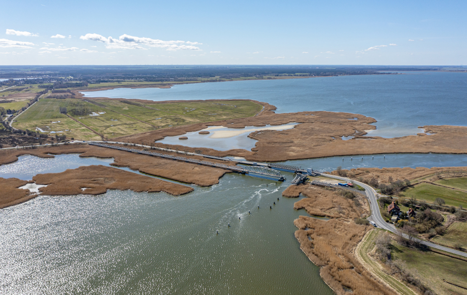 Luftaufnahme der bestehenden Meiningenbrücke mit umliegenden Wasserflächen, Schilfbereichen und angrenzender Landschaft.