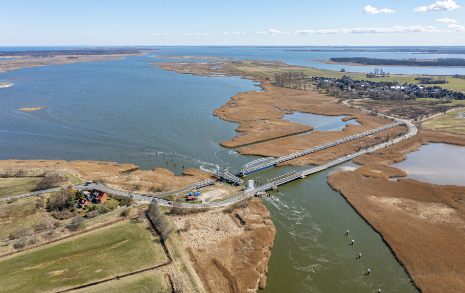 Luftaufnahme der bestehenden Meiningenbrücke mit Zufahrtsstraßen, Wasserflächen und weitläufiger Boddenlandschaft.