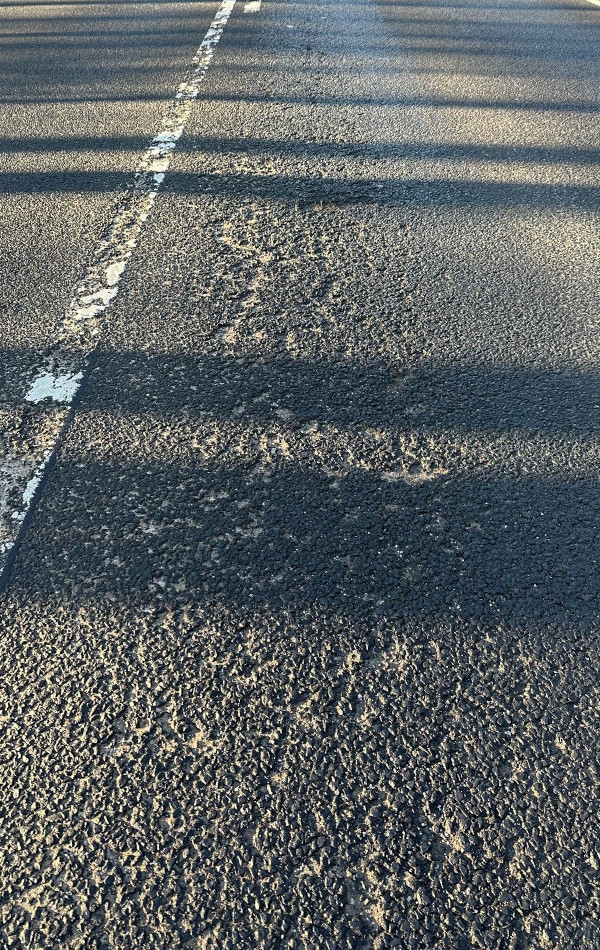 Auf dem Asphalt einer Straße sind lauter kleine Erhebungen.