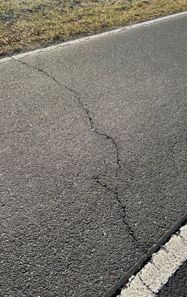 In einer Asphaltstraße ist ein Riss quer über die Fahrbahn.