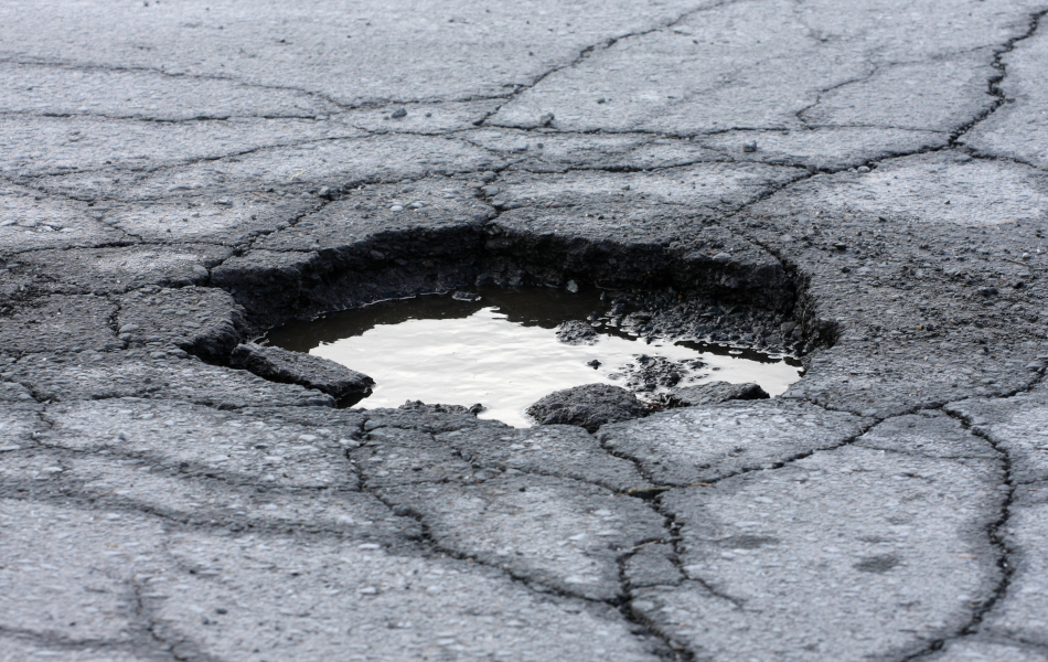 Eine Asphaltdecke ist aufgebrochen und hat ein Loch.