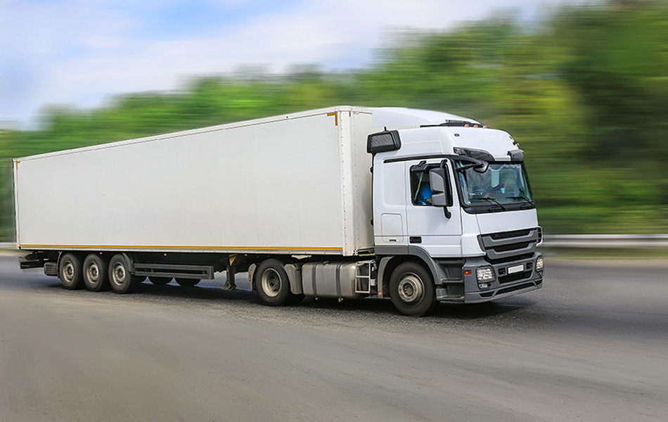Ein großer, weißer LKW fährt auf einer Straße.