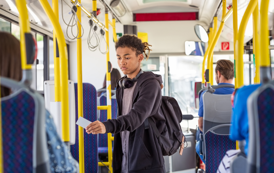 Ein Teenager bezahlt kontaktlos im öffentlichen Nahverkehr. Der Junge benutzt dafür eine Chipkarte im Bus. Er trägt Freizeitkleidung.